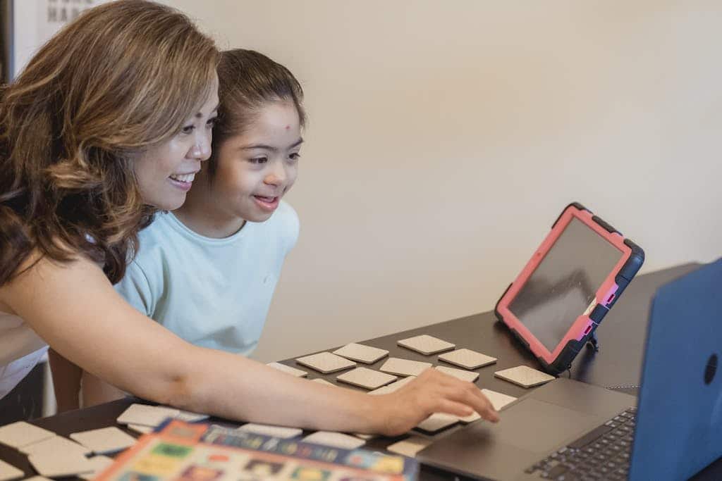 Asian mother and daughter enjoying learning together with a laptop and educational cards indoors.