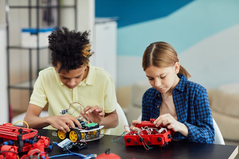 Two teenagers collaborating on a robotics project, focusing on circuitry and innovation.